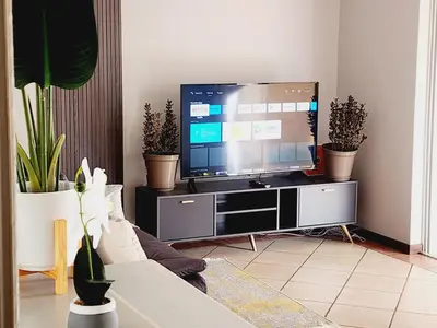 a living room with a flat screen tv on a entertainment center at Lemon tree in Pretoria