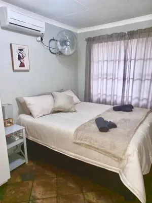 a bedroom with a bed with a fan and a window at Numida Rus in Marloth Park