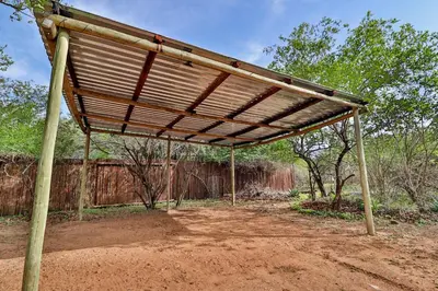 awning over a dirt field with a fence at Numida Rus in Marloth Park