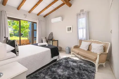 a bedroom with a bed and a chair and a window at Expansive 5-bedroom house in Hartbeespoort