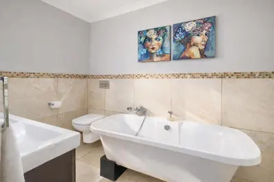 a bathroom with a tub and a sink and a toilet at Expansive 5-bedroom house in Hartbeespoort