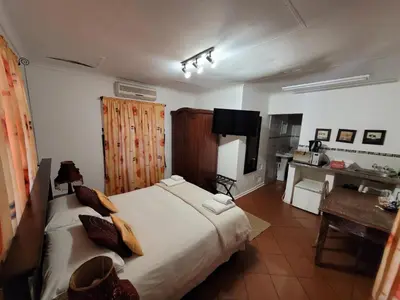 a bedroom with a large white bed and a desk at Pebble Fountain Guesthouse in Pretoria