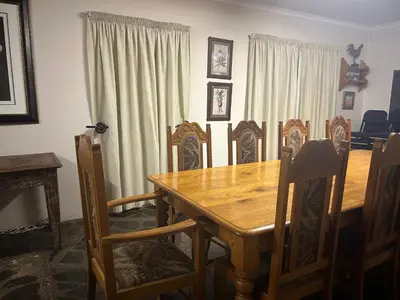 a dining room with a wooden table and chairs at Pebble Fountain Guesthouse in Pretoria
