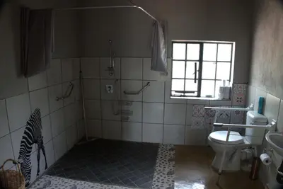a bathroom with a toilet and a sink and a window at Marty's Rest in Marloth Park