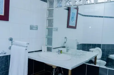 a white bathroom with a sink and a toilet at 129inHarties Lodge and SPA in Hartbeespoort