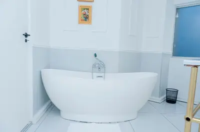 a white bathroom with a large white bath tub at 129inHarties Lodge and SPA in Hartbeespoort