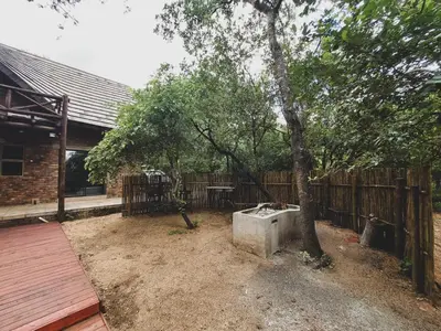 a backyard with a tree and a wooden fence at HUIS ASEM in Marloth Park