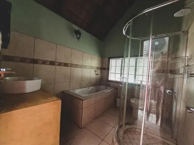 a bathroom with a shower and a sink and a tub at HUIS ASEM in Marloth Park