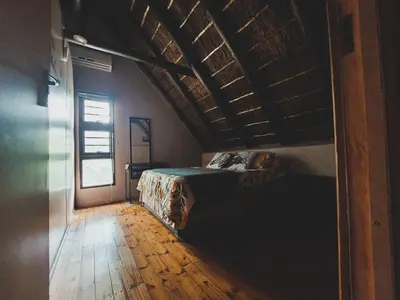 a bedroom with a bed and a wooden floor at HUIS ASEM in Marloth Park