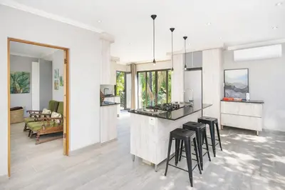 a kitchen and living room with a counter and stools at Apartment at Magalies Edge in Hartbeespoort