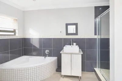 a white bathroom with a tub and a sink at Apartment at Magalies Edge in Hartbeespoort