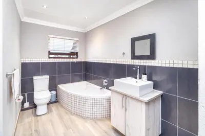 a bathroom with a tub and a toilet and a sink at Apartment at Magalies Edge in Hartbeespoort