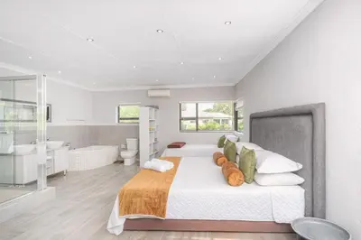 a bedroom with a large bed and a bath room at Apartment at Magalies Edge in Hartbeespoort