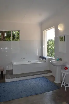 a white bathroom with a tub and a sink at Kruger Park Farmstay near Orpen Gate in Hoedspruit