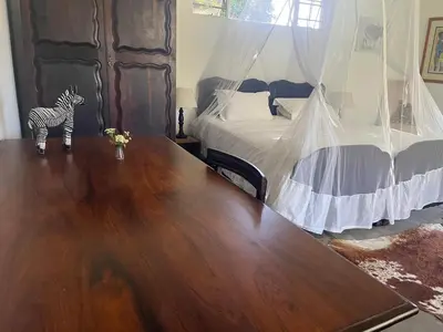 a room with a wooden table and a bed with a zebra statue at Kruger Park Farmstay near Orpen Gate in Hoedspruit
