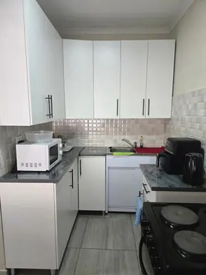 a kitchen with white cabinets and a microwave at Peshline Guest House Unit 1 in Ermelo