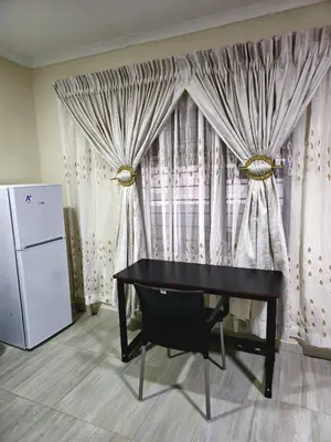 a black desk in front of a window with curtains at Peshline Guest House Unit 1 in Ermelo