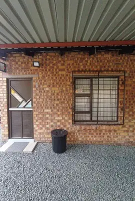 a brick building with two windows and a trash can at Peshline Guest House Unit 1 in Ermelo