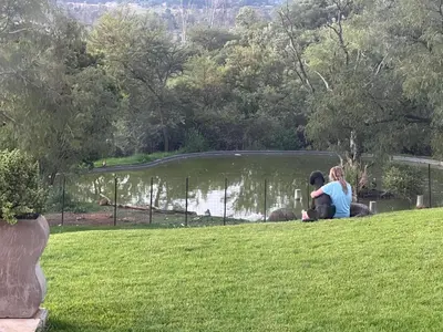 two women sitting on the grass near a pond at Mountain Haven in Pretoria