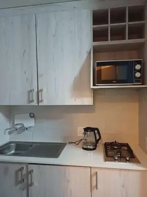 a kitchen with a sink and a microwave and a stove at Buhle Guesthouse in Sandton