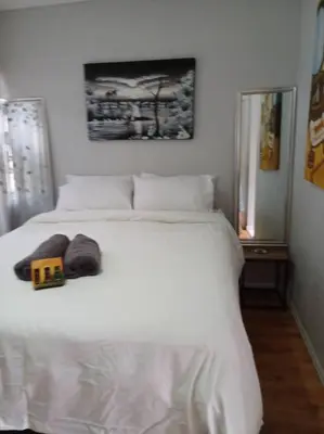 a bedroom with a white bed with a toy house on it at Buhle Guesthouse in Sandton