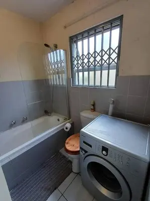 a bathroom with a washing machine and a bath tub at Buhle Guesthouse in Sandton