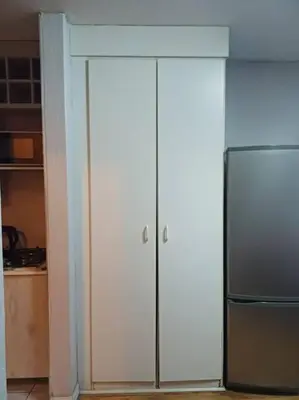 a kitchen with two white cabinets and a refrigerator at Buhle Guesthouse in Sandton