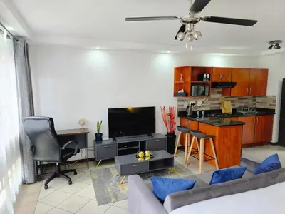 a living room with a couch a table and a kitchen at MPASSI Properties - Hatfiled, Pretoria in Pretoria