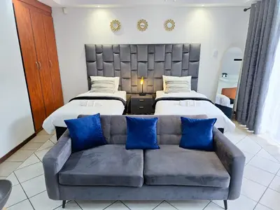 a living room with two beds and a couch at MPASSI Properties - Hatfiled, Pretoria in Pretoria