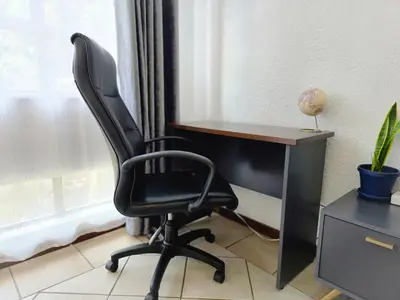 a black office chair sitting next to a desk at MPASSI Properties - Hatfiled, Pretoria in Pretoria