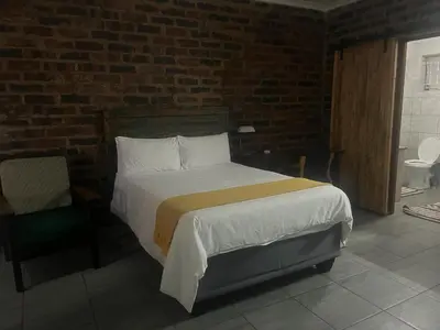 a bedroom with a bed and a brick wall at @Eland B&B in Mokopane