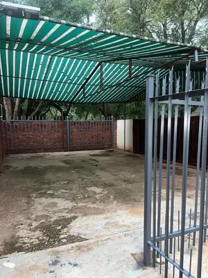 a green canopy over a parking lot with a fence at @Eland B&B in Mokopane