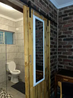 a bathroom with a toilet and a brick wall at @Eland B&B in Mokopane