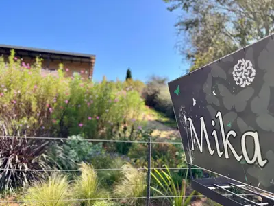 a sign in front of a garden with plants at Mika Self Catering Cottage in Dullstroom