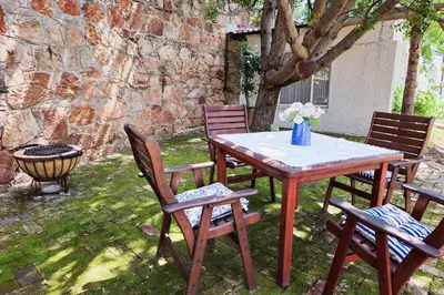 a wooden table with chairs and a table with flowers on it at Dutch on Tecoma, Wonderboom, Pretoria in Pretoria