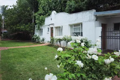 a white house with white roses in the yard at Dutch on Tecoma, Wonderboom, Pretoria in Pretoria