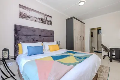 a bedroom with a large bed with colorful pillows at The Resting Nest Delight in Midrand