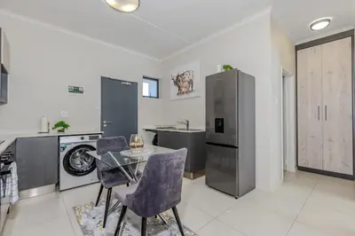 a kitchen with a glass table and a refrigerator at The Resting Nest Delight in Midrand