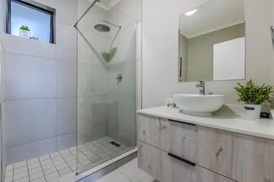 a white bathroom with a sink and a shower at The Resting Nest Delight in Midrand