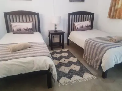 a bedroom with two beds and a table with a lamp at Paperbark Self Catering Units in Doornfontein