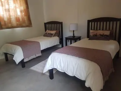 a bedroom with two beds and a lamp in it at Paperbark Self Catering Units in Doornfontein