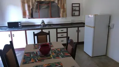 a kitchen with a table and a white refrigerator at Paperbark Self Catering Units in Doornfontein