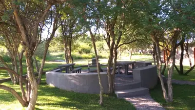 a park with picnic tables and trees in the grass at Paperbark Self Catering Units in Doornfontein