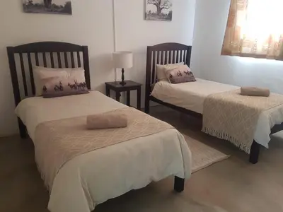 a room with two beds with pillows on them at Paperbark Self Catering Units in Doornfontein