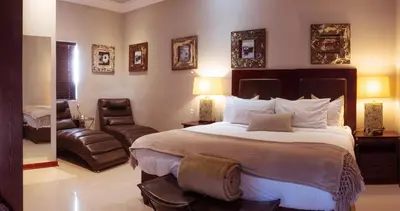 a bedroom with a large bed and a chair at Tuareg Guest House in Midrand