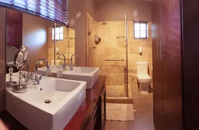 a bathroom with two sinks and a shower and a toilet at Tuareg Guest House in Midrand