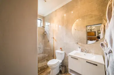 a bathroom with a toilet and a sink and a mirror at Tuareg Guest House in Midrand