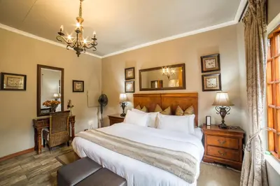 a bedroom with a large bed and a chandelier at Tuareg Guest House in Midrand