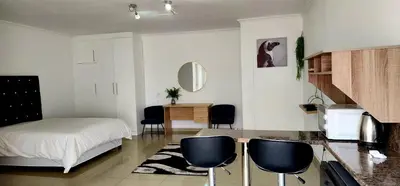 a bedroom with a bed and chairs in a room at Khayelihle Guest house in Benoni