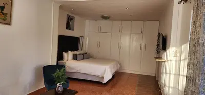 a bedroom with a bed and a large white cabinet at Khayelihle Guest house in Benoni